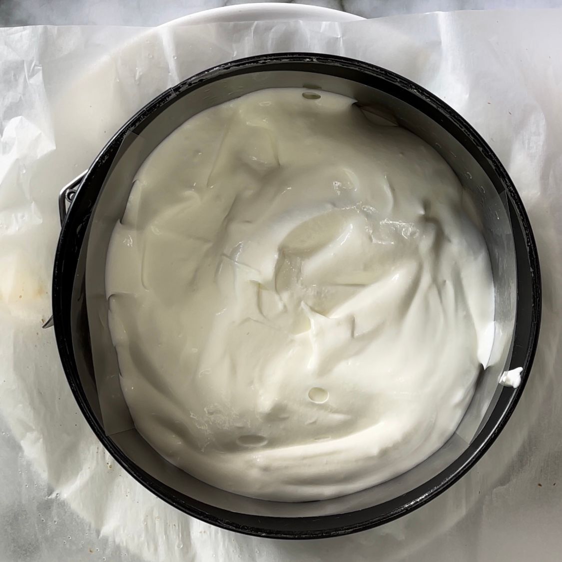 Una ciotola di panna montata è appoggiata su un pezzo di carta oleata.