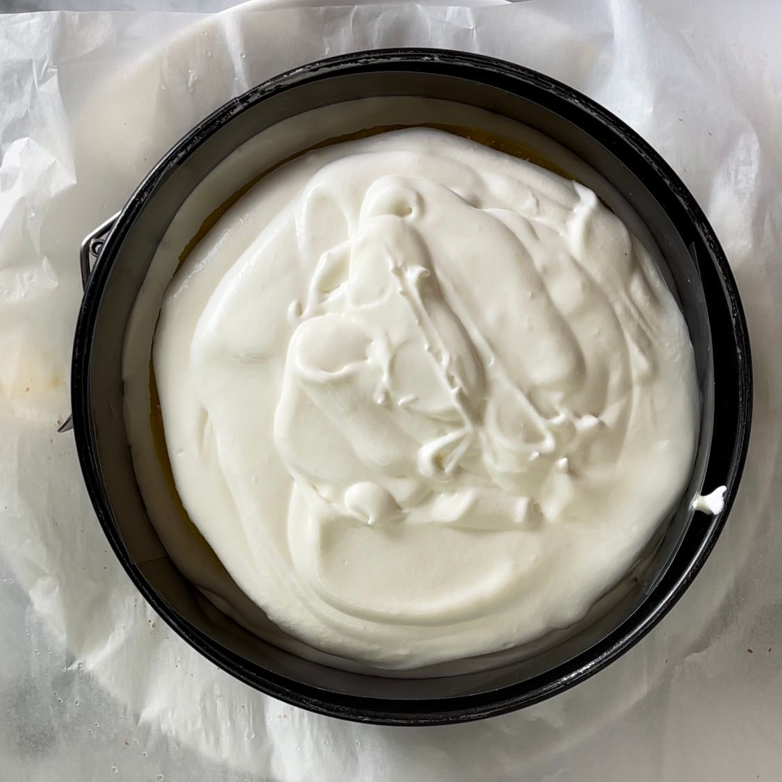 Una padella nera riempita di glassa bianca su un pezzo di carta oleata