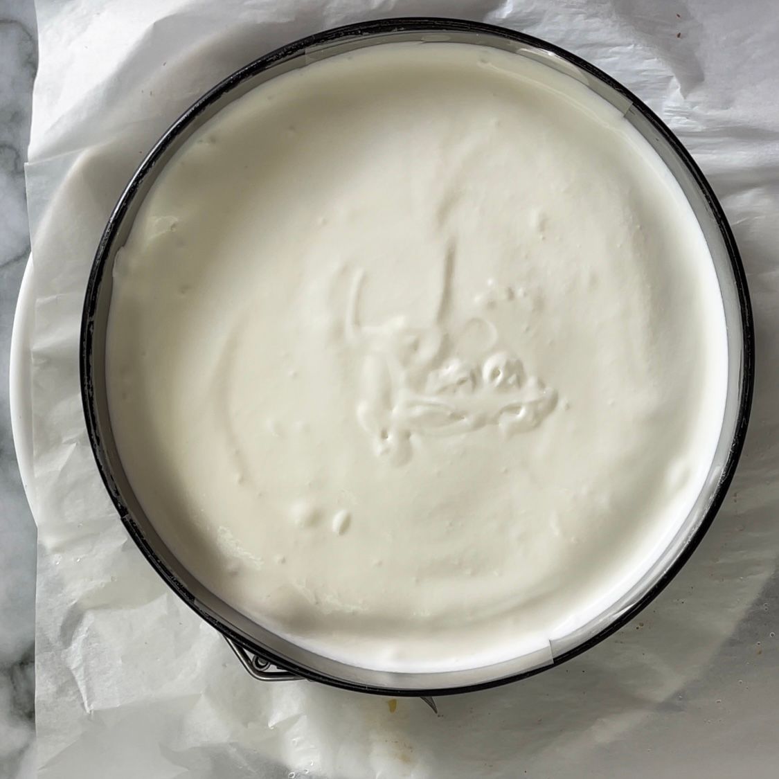 Una ciotola di yogurt è appoggiata su un pezzo di carta oleata.