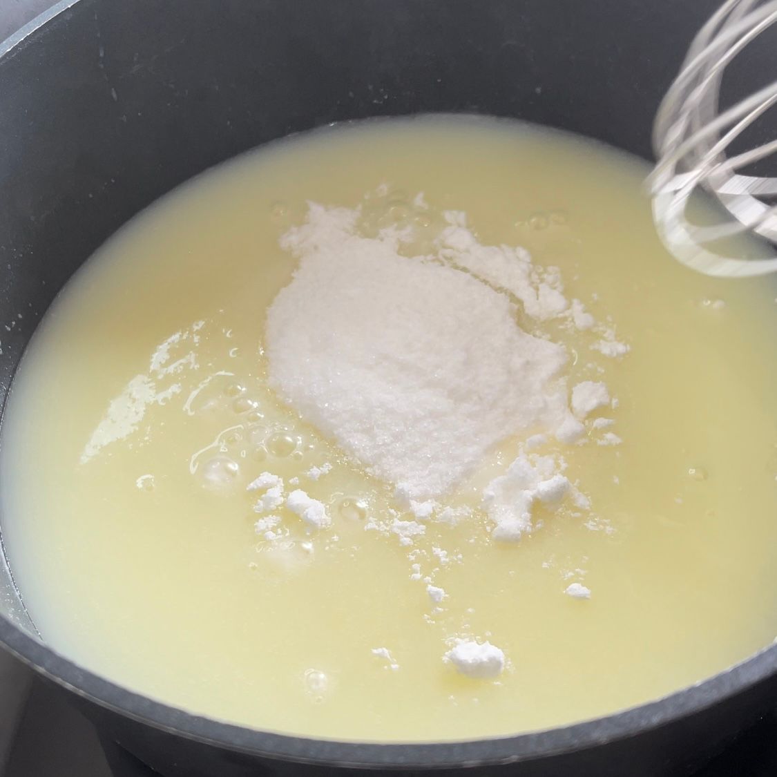 Un primo piano di una pentola di zuppa con una frusta dentro.