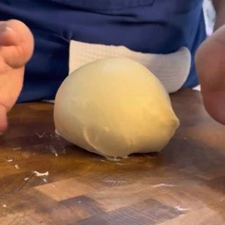 Una persona tiene in mano una palla di pasta su un tagliere
