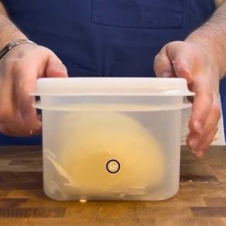 Una persona tiene in mano un contenitore di plastica con dentro un impasto