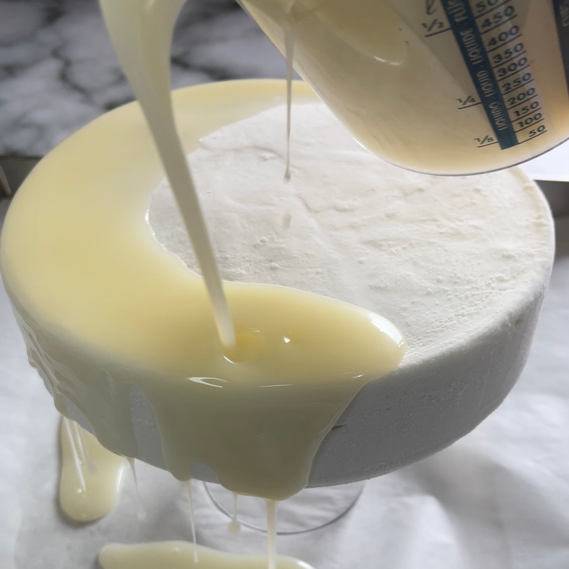 Una persona sta versando del liquido da un misurino in una torta