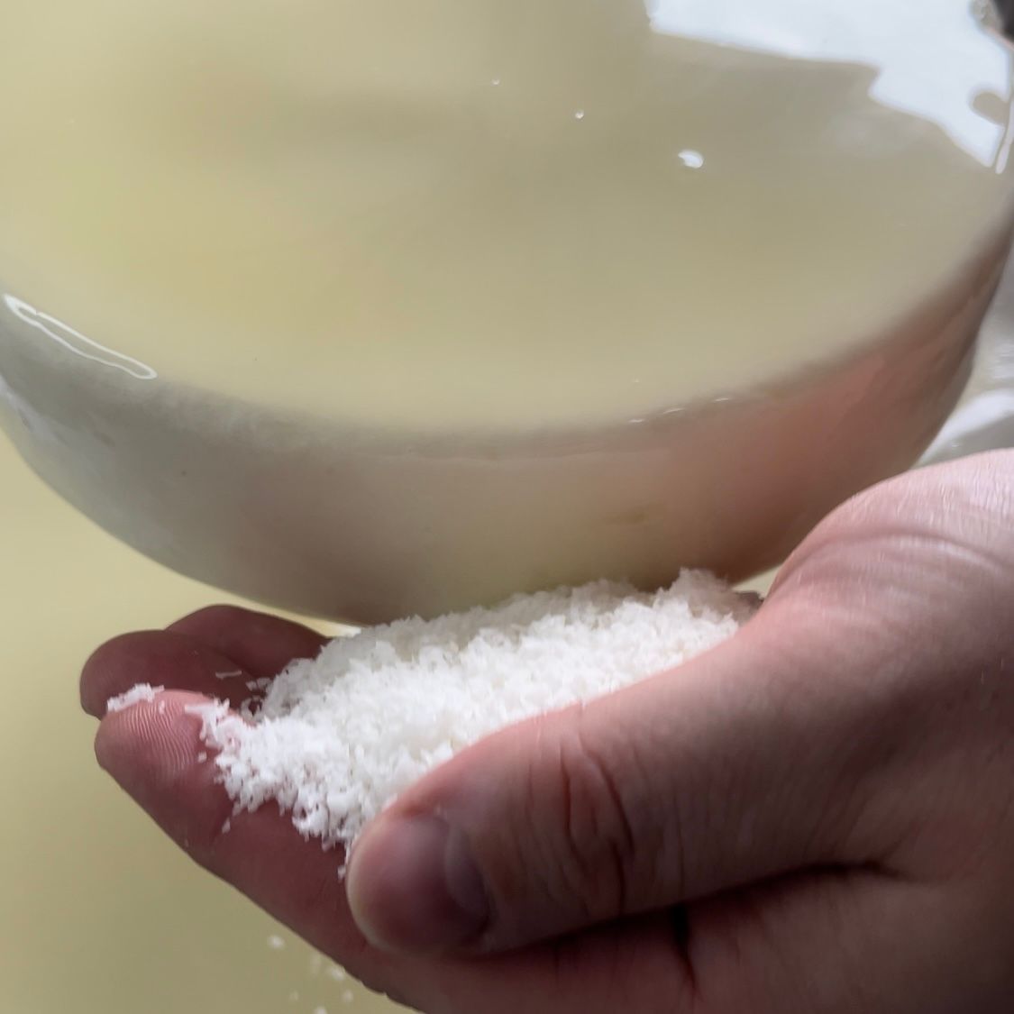 Una persona tiene una manciata di sale davanti a una ciotola d'acqua