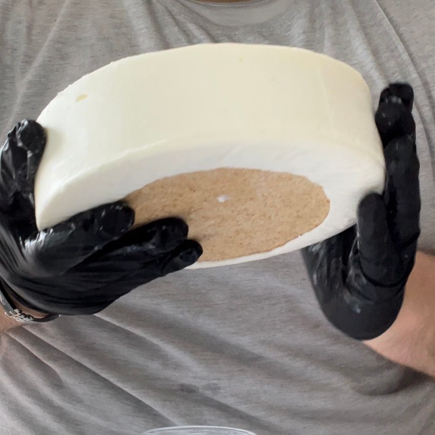 Una persona che indossa guanti neri tiene in mano un oggetto bianco