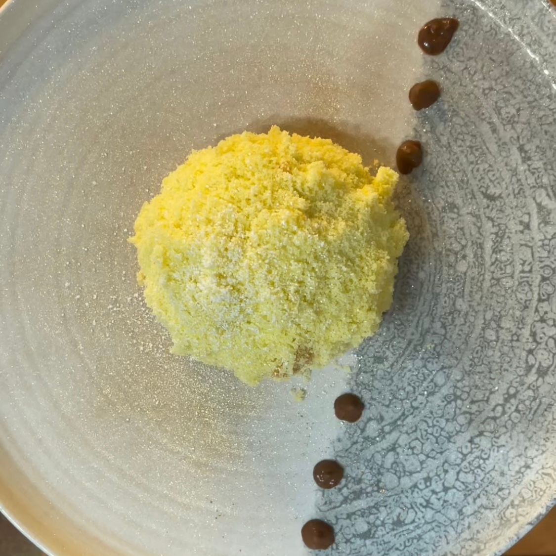 Un piatto bianco con una piccola pallina gialla sopra