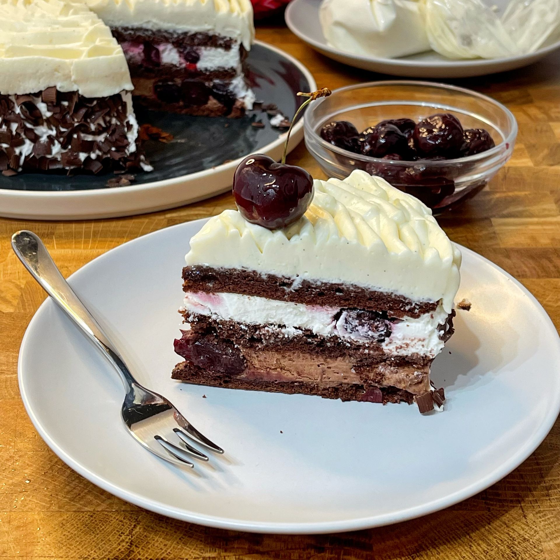 Una fetta di torta Foresta Nera su un piatto bianco con una forchetta.