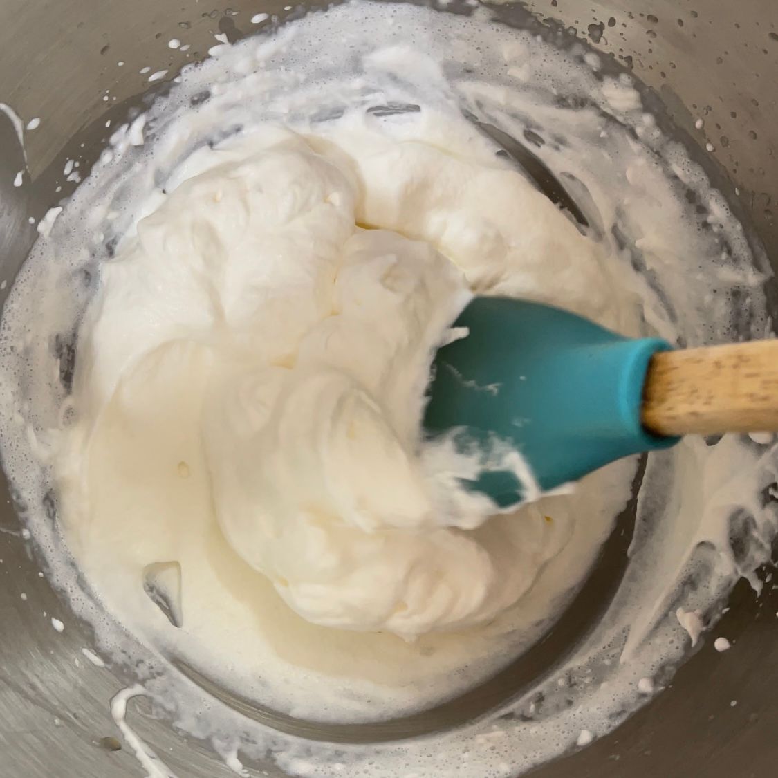 Una spatola blu è in una ciotola di panna montata