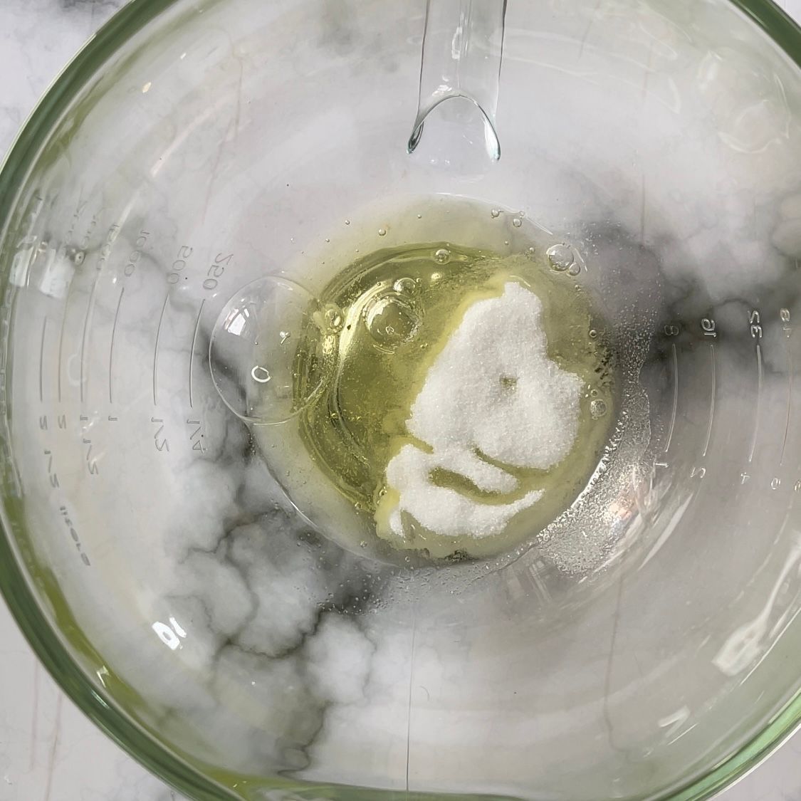 Un misurino di vetro pieno di liquido e zucchero.