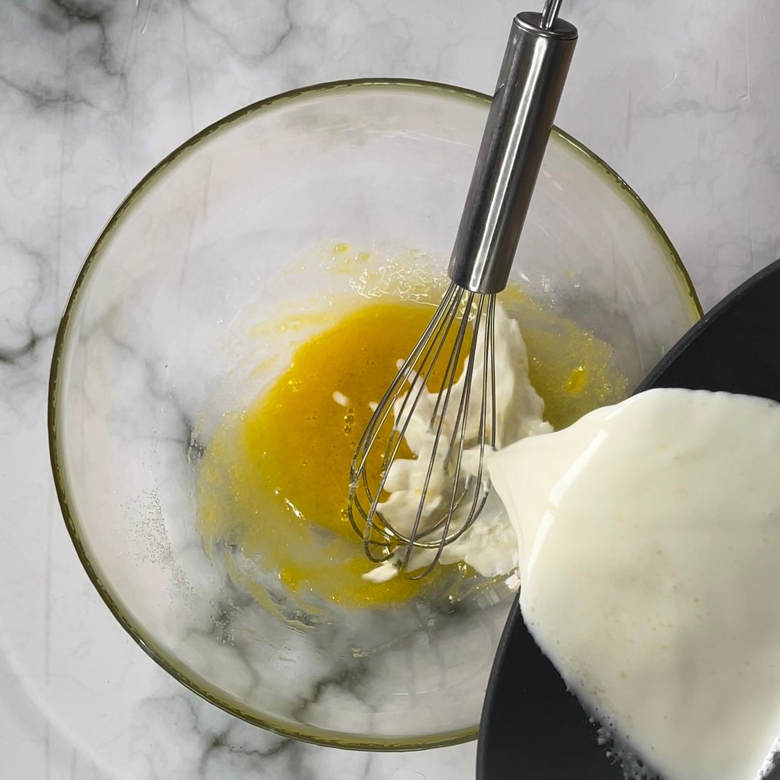 Una frusta viene versata in una ciotola con uova e panna montata.