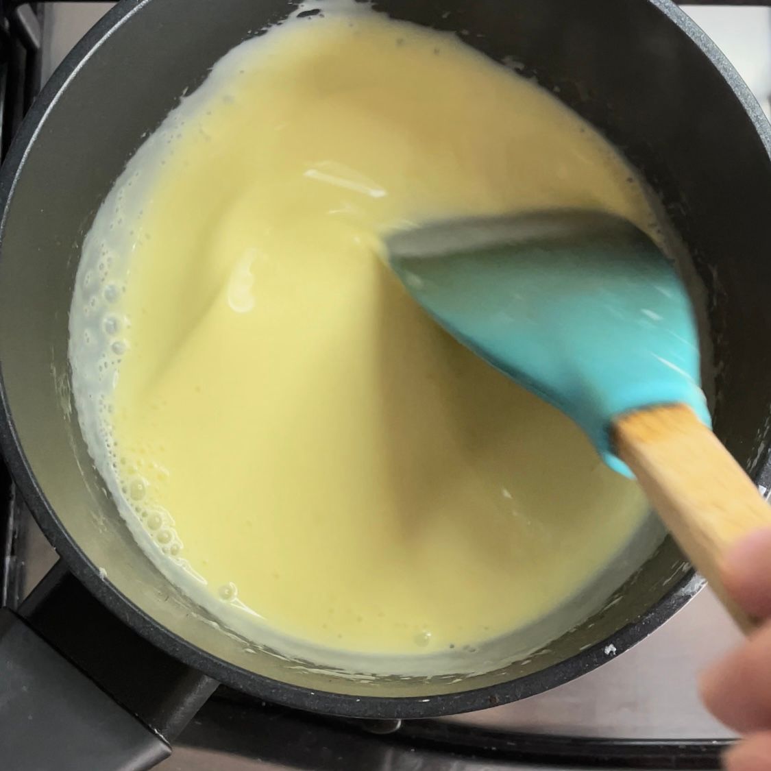 Una persona sta mescolando un liquido giallo con una spatola blu