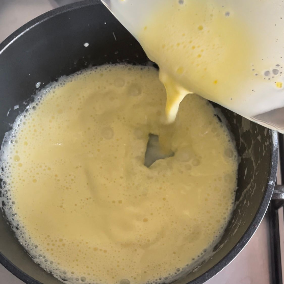 Una persona sta versando un liquido giallo in una pentola