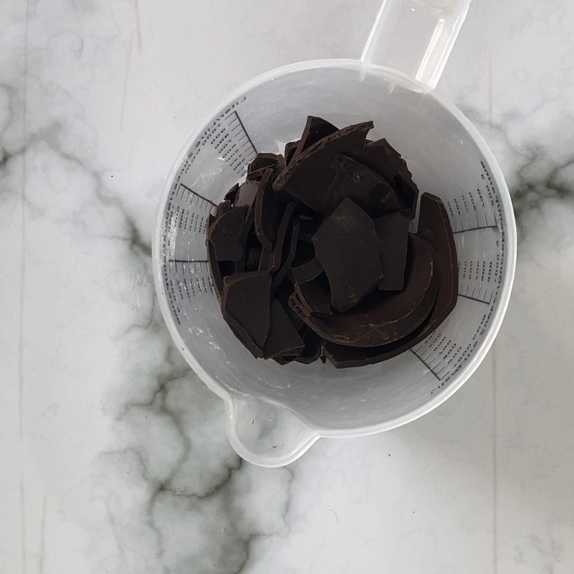 Un misurino pieno di pezzetti di cioccolato su un tavolo.