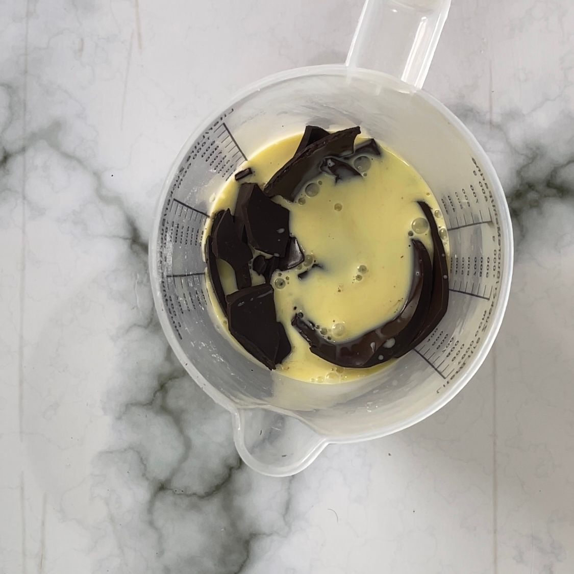 Un misurino pieno di cioccolato e liquido su un tavolo.