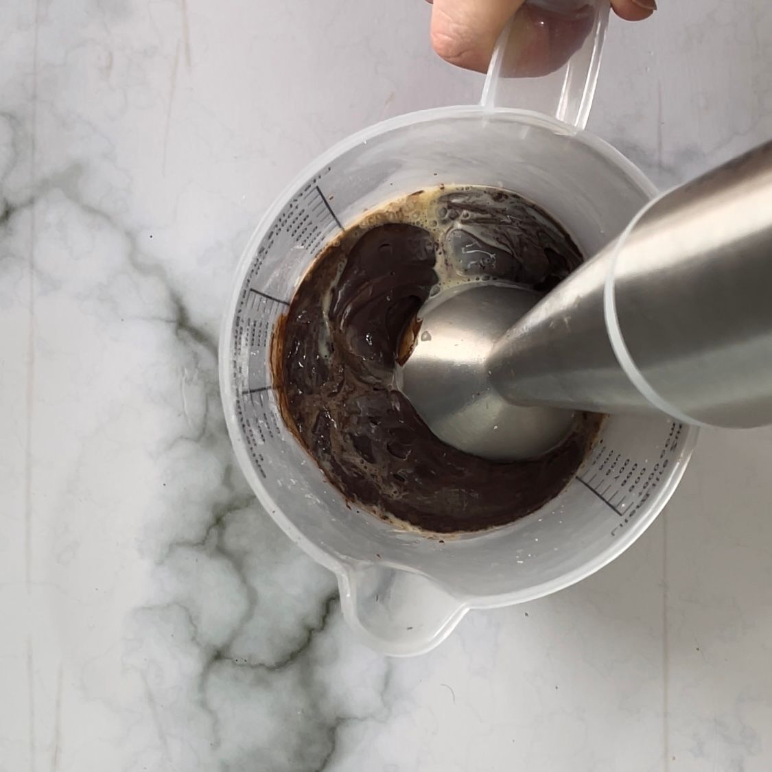 Una persona sta versando del cioccolato in un misurino.