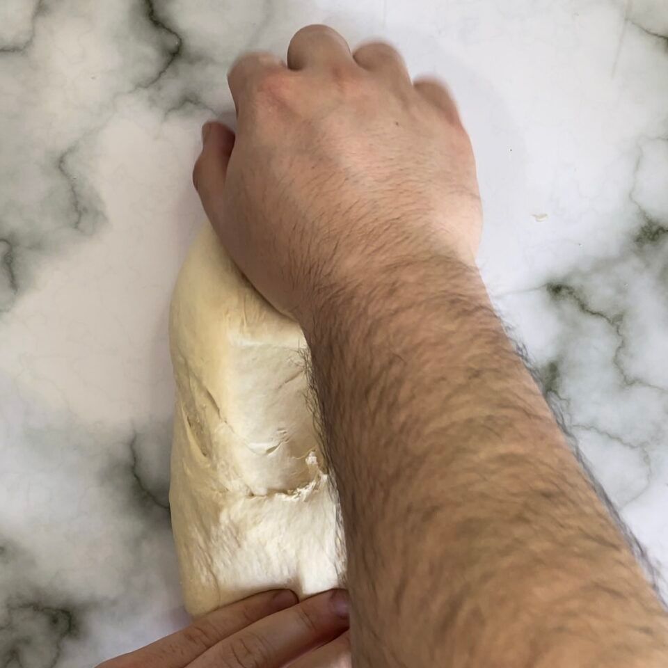 Una persona sta impastando l'impasto su una superficie di marmo.