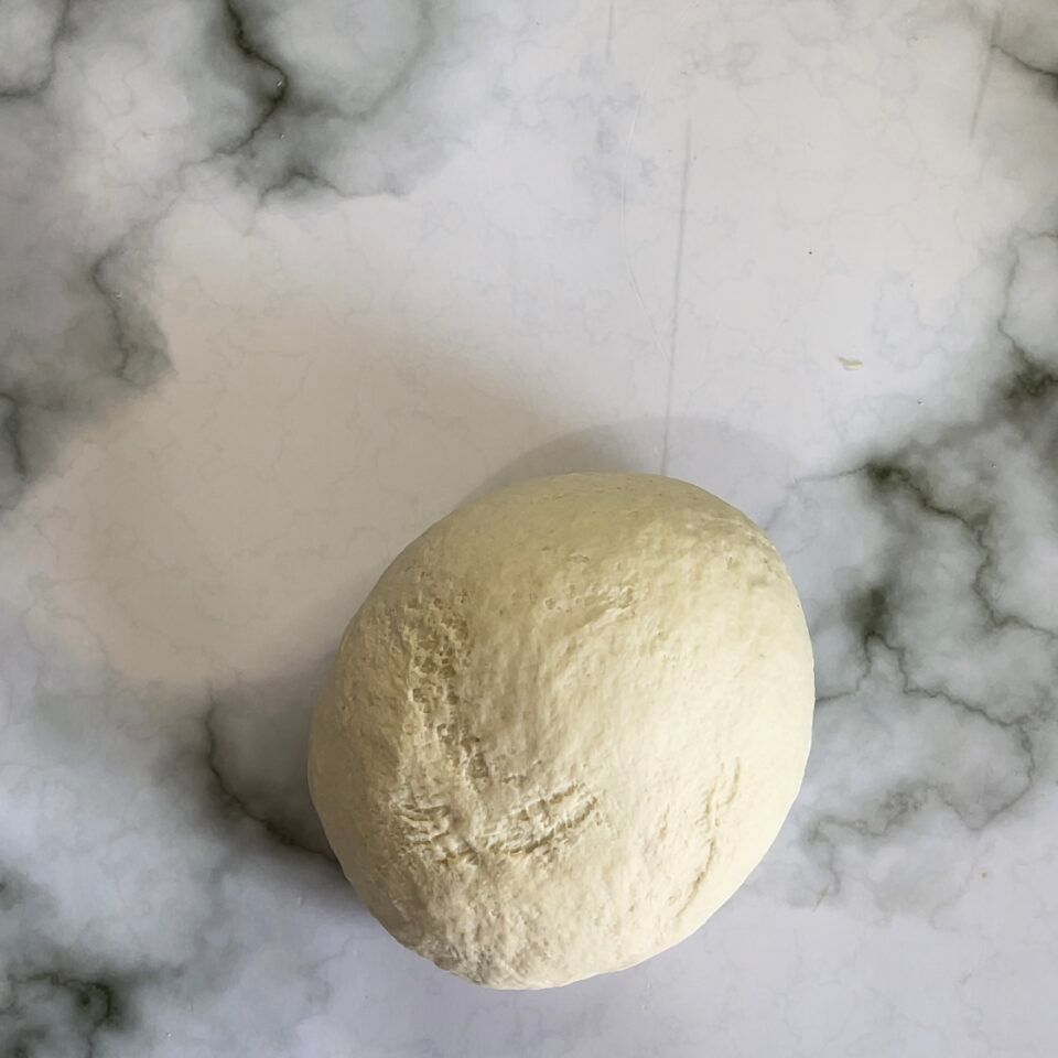 Una palla di pasta è appoggiata su una superficie di marmo.