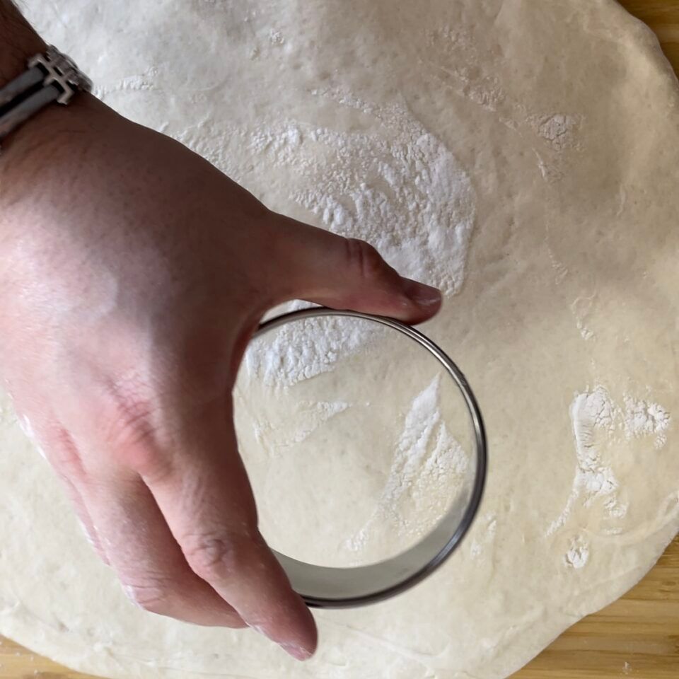 Una persona sta usando un tagliabiscotti su un pezzo di pasta