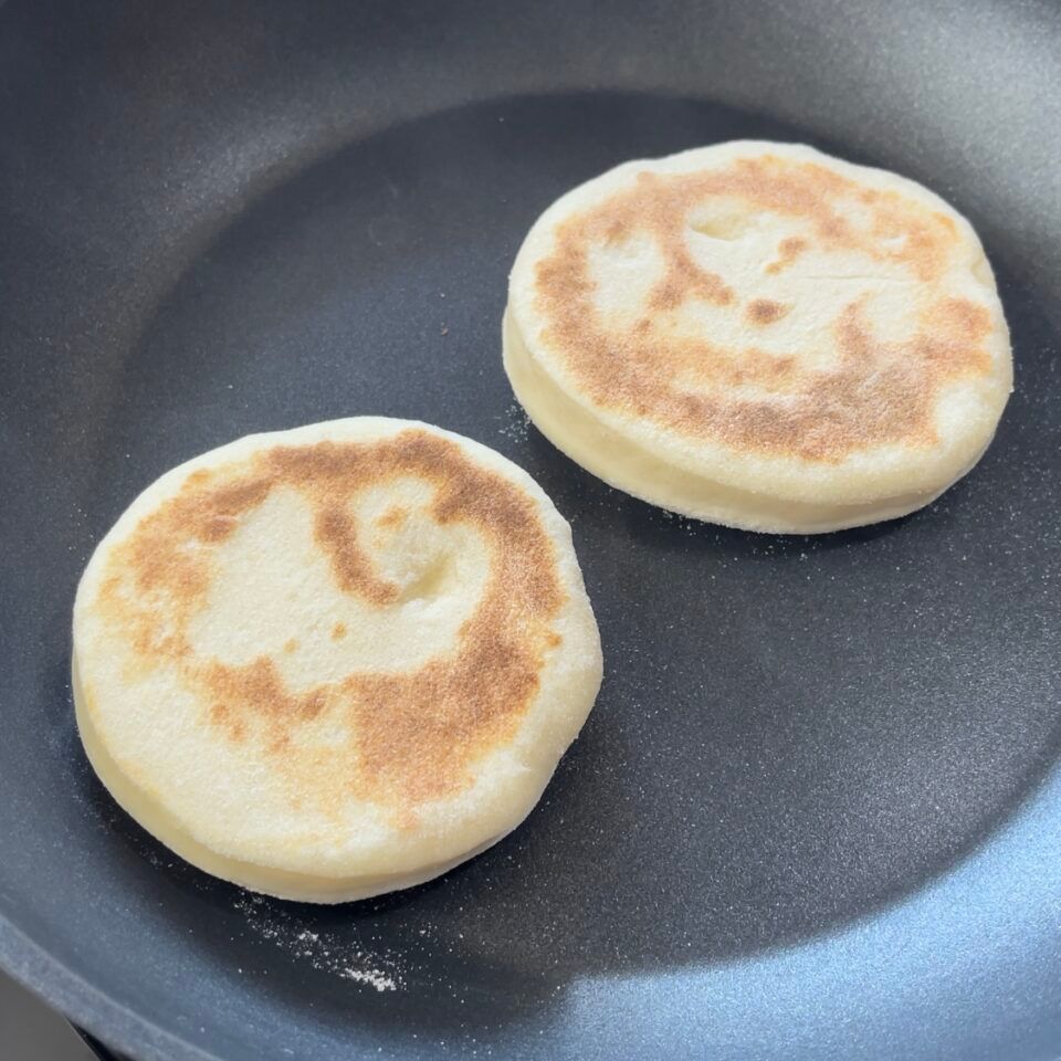 Due muffin inglesi vengono cotti in una padella