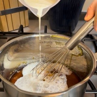 Una persona che versa del liquido in una pentola con una frusta