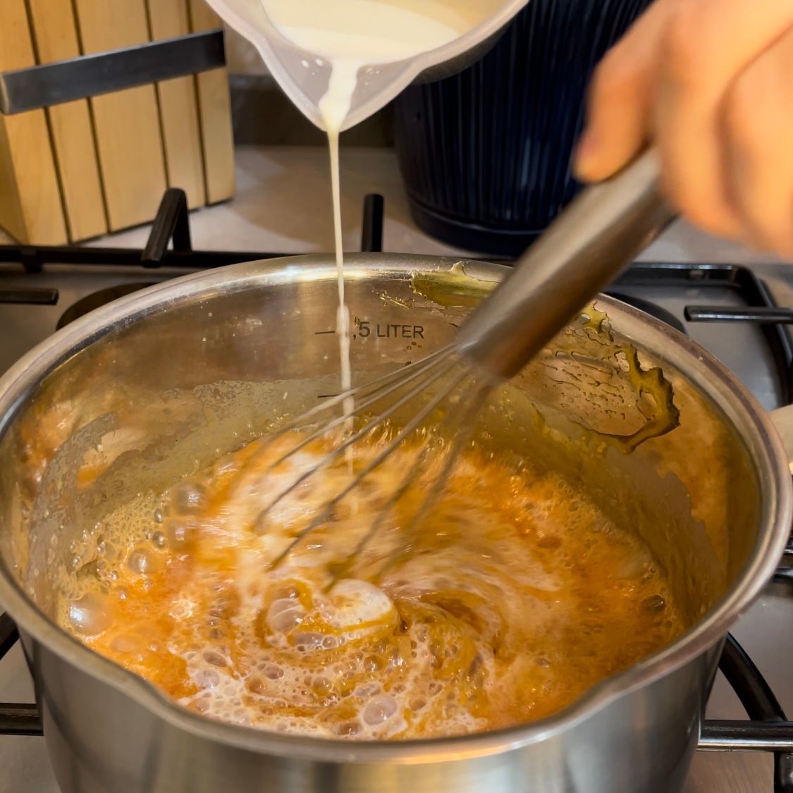 Una persona sta versando il latte in una pentola con una frusta