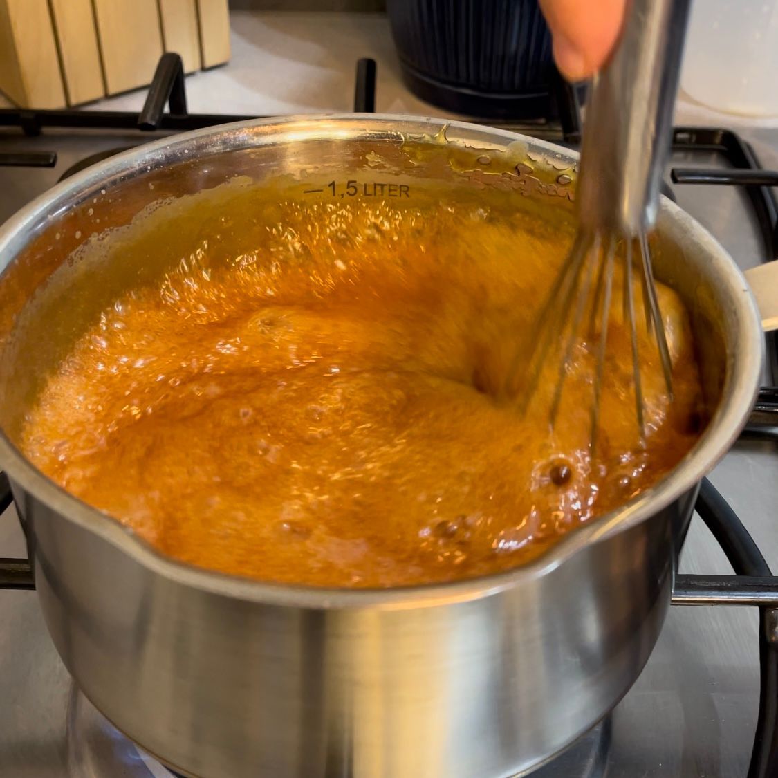 Una persona sta mescolando una pentola di salsa su un fornello