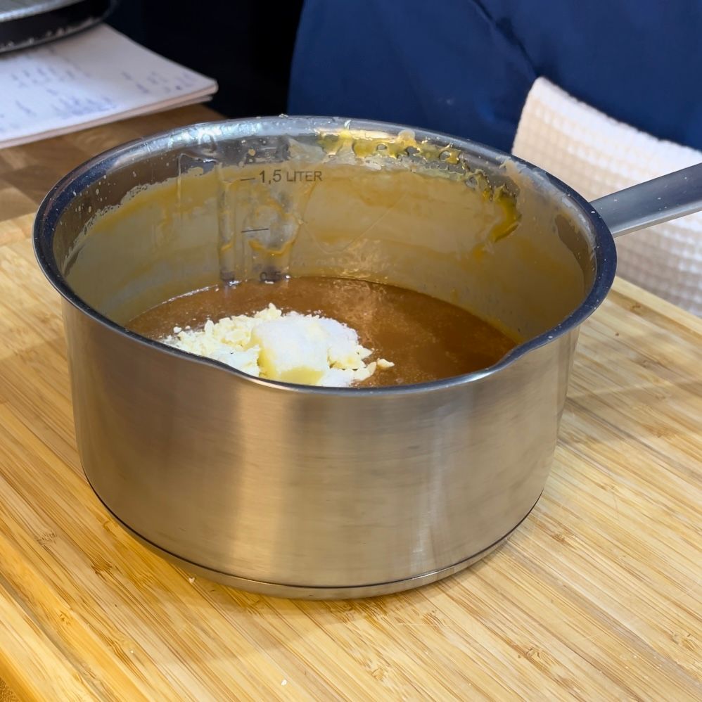 Una pentola di salsa è su un tagliere di legno