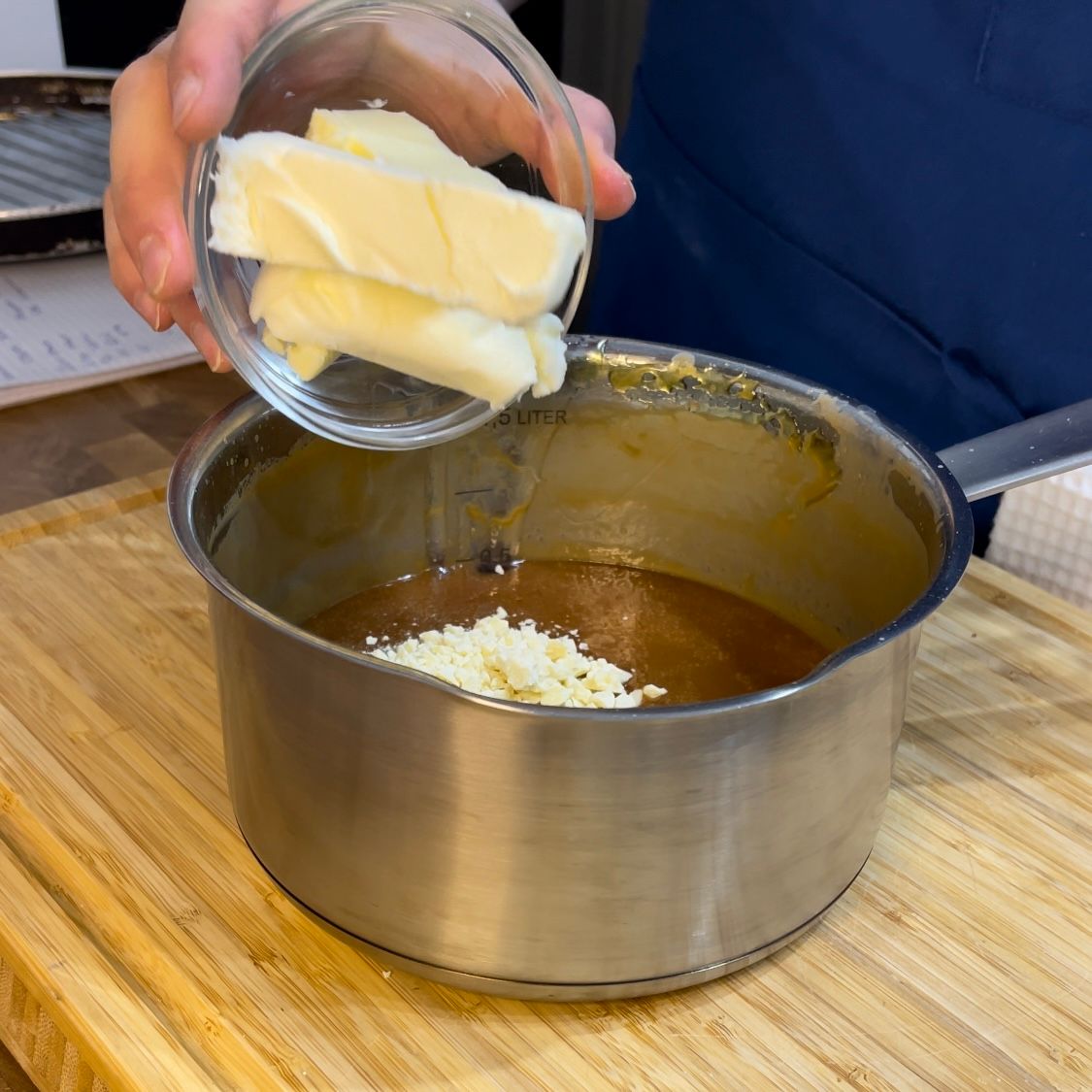 Una persona sta versando il burro in una pentola di salsa.