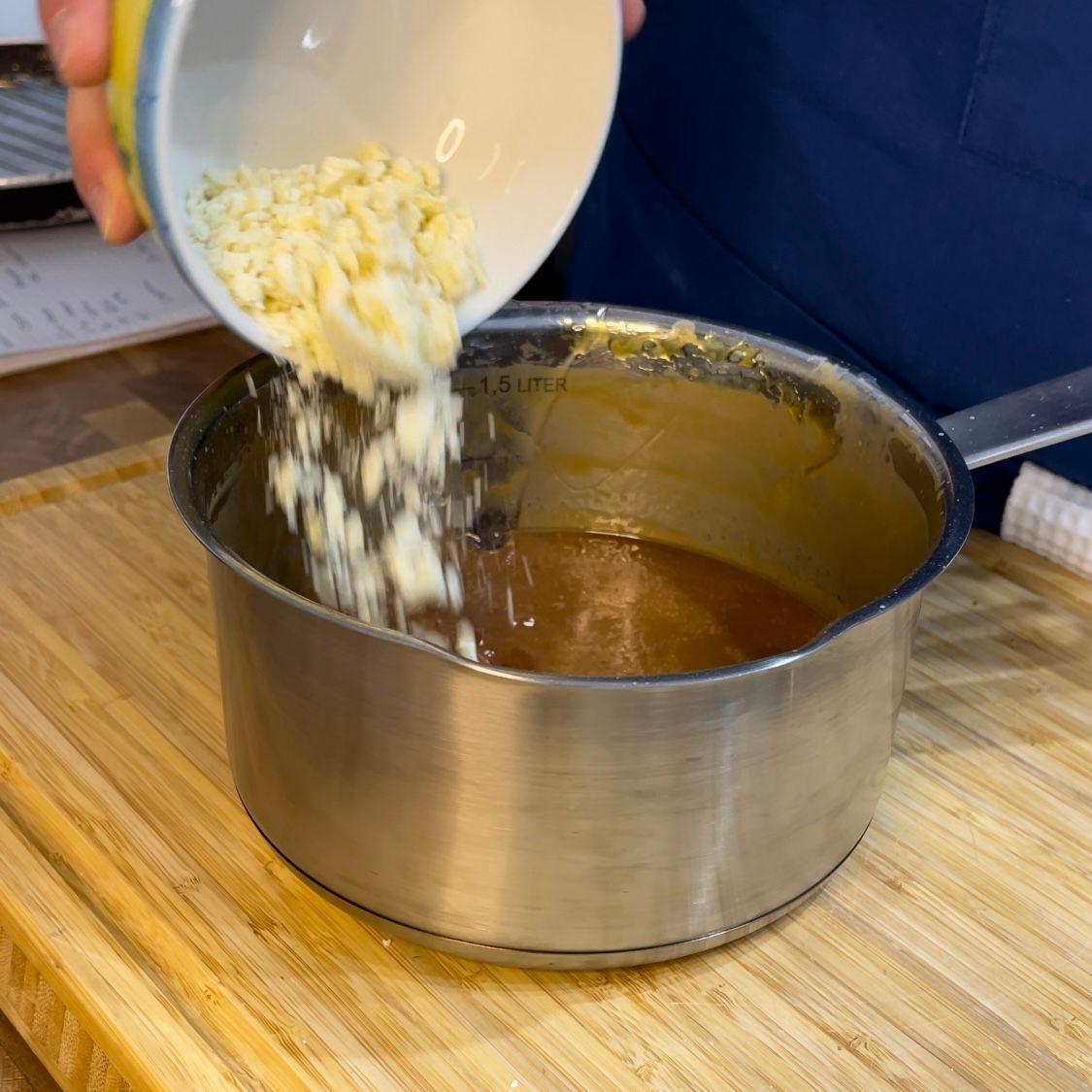 Una persona sta versando qualcosa in una pentola su un tagliere