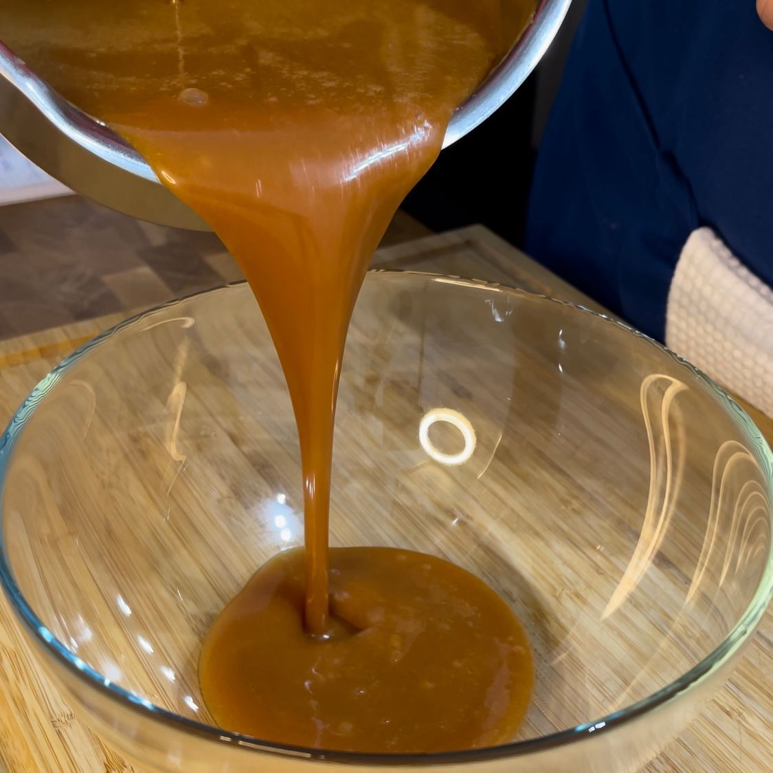 Una persona che versa un liquido marrone in una ciotola di vetro