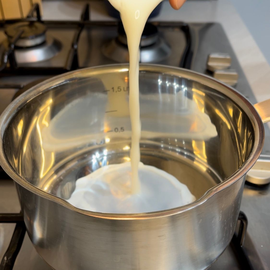 Una persona sta versando del liquido in una pentola su cui è scritto il numero 1,5