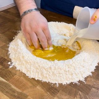 Una persona sta versando del liquido in un mucchio di farina