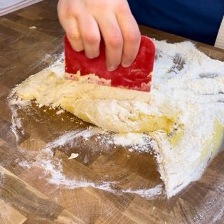 Una persona sta usando una spatola rossa su un pezzo di pasta