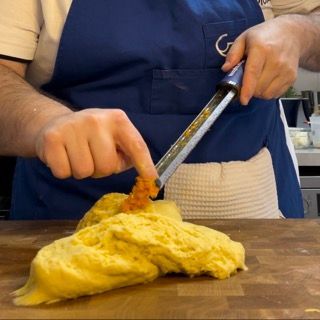 Una persona con un grembiule blu sta tagliando un pezzo di cibo su un tagliere