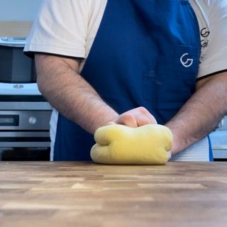 Un uomo che indossa un grembiule blu con la lettera g sopra