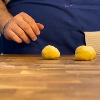Due palline di pasta gialla sono su un tavolo di legno