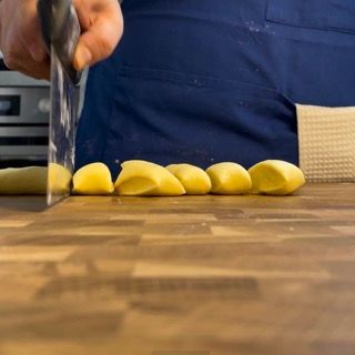 Una persona sta tagliando le patate su un tagliere di legno