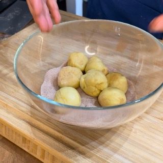 Una ciotola di vetro piena di patate è su un tagliere di legno