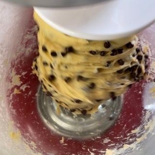 Impasto con gocce di cioccolato rovesciato su un piano di lavoro infarinato.