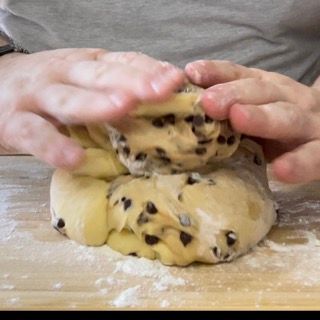 Mani che eseguono una piega sull'impasto per dargli una forma rotonda.