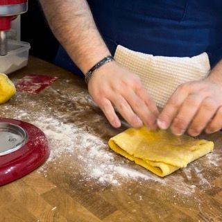Una persona sta impastando un pezzo di pasta su un tavolo di legno