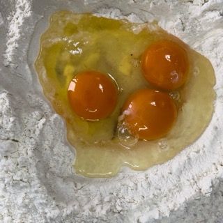 Tre uova sono appoggiate su un mucchio di farina.