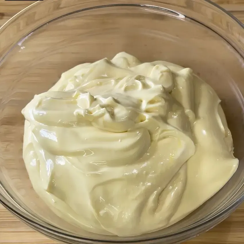 Una ciotola di maionese su un piatto con un cucchiaio