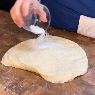 Una persona sta versando il sale in un pezzo di impasto