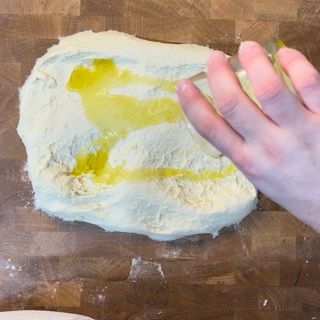 Una persona sta versando dell'olio su un pezzo di pasta