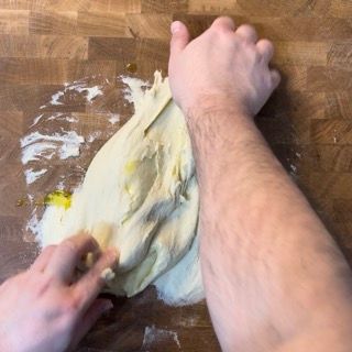 Una persona sta impastando la pasta su un tavolo di legno