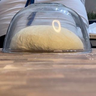 Una palla di pasta è posta sotto una cupola di vetro su un tavolo di legno.