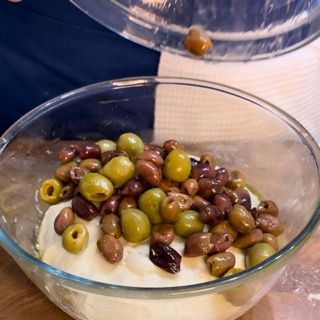 Una ciotola di vetro piena di olive e yogurt