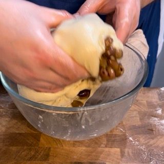 Una persona tiene in mano un pezzo di impasto in una ciotola di vetro.