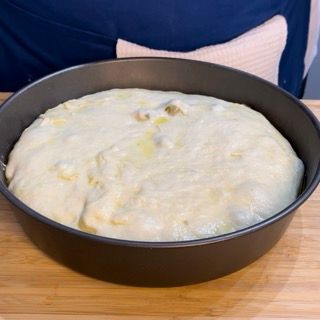 Una teglia di pasta è appoggiata su un tavolo di legno.